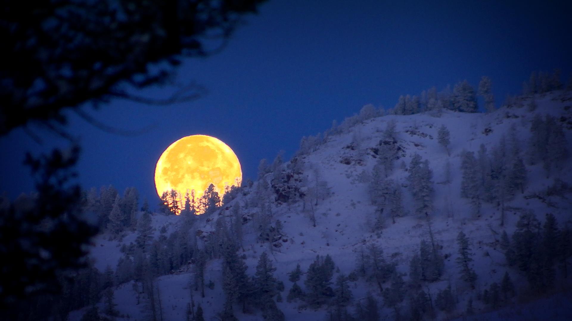 moon setting behind the bridge mountain in Montana
