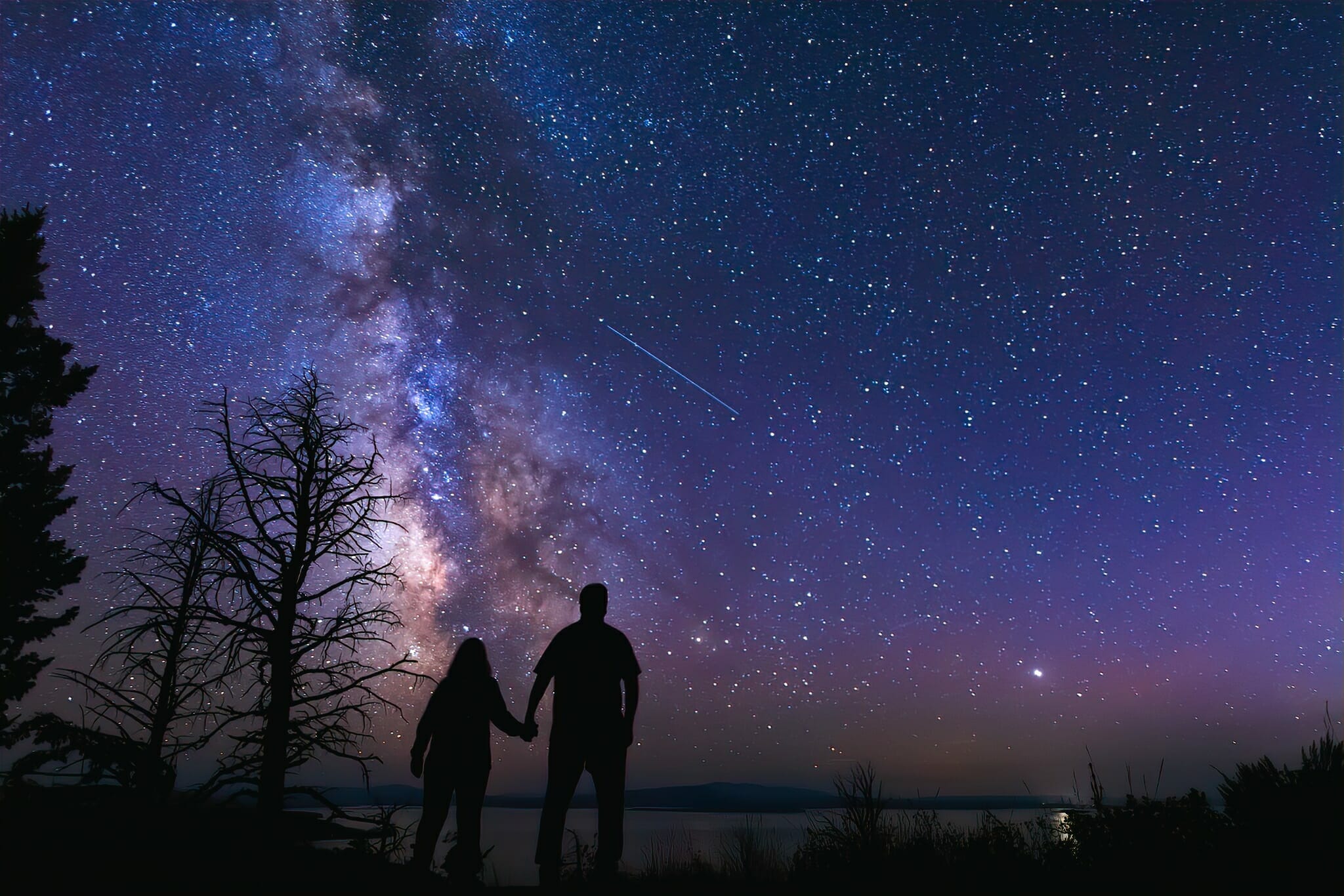 Happy couple standing in front of the Milky Way in Yellowstone National Park